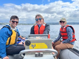 Three UW researchers in a boat wearing life jackets